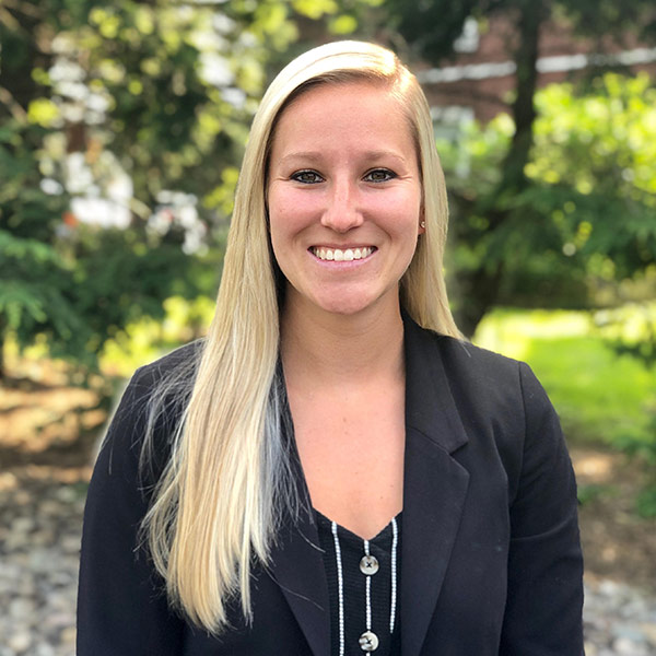 Allison Cressman Durnin wearing a black dress shirt under a black suit jacket standing in front of landscaped lawn at D.E. Cressman Insurance Agency Inc. in Allentown, PA