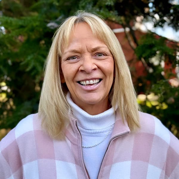 Maryann Paluch wearing a white and pink sweater standing on a paved lot at D.E. Cressman Insurance Agency Inc. in Allentown, PA.